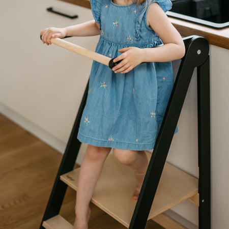 Roomix toddler tower with child standing safely inside, demonstrating height and secure handrails for learning